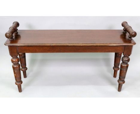 A late Victorian oak hall bench, with ring turned roll arms, the moulded rectangular seat with canted corners, on ring turned