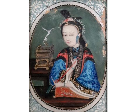 A Chinese portrait of a woman, 18th/19th Century, sewing at a table, a censer to her left hand side, gouache on glass in a pa