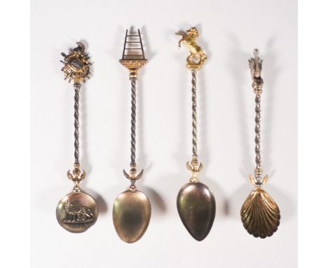 set of four gilt metal collector spoons featuring elaborately twisted handles and finely detailed figural finials. Each spoon