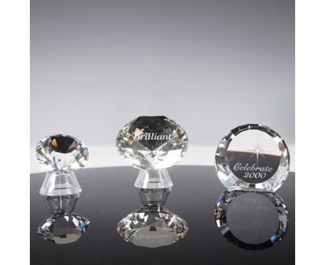 A set of three Swarovski crystal paperweights, each featuring intricate faceting that captures and refracts light beautifully
