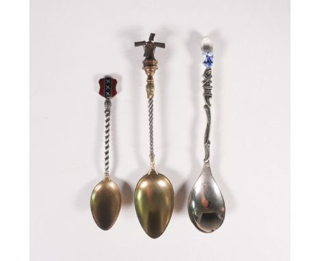A set of three vintage Dutch souvenir spoons, each showcasing unique regional elements. One spoon features a windmill finial 