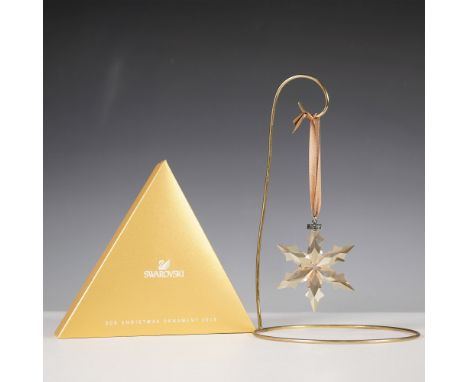 A delicate and radiant Swarovski 2015 SCS Christmas Ornament, featuring a faceted golden-hued snowflake with intricate detail