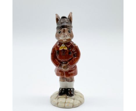 This charming Royal Doulton Bunnykins figurine, titled "Brownie Bunnykins," features a detailed depiction of a young rabbit d