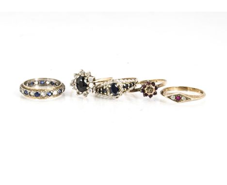 A collection of five gem set dress rings, including a sapphire example, a three stone ruby and diamond ring, a garnet and dia