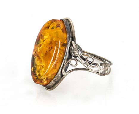 A large amber and silver bangle, the oval polished stone of navette shape in white metal floral wirework setting, 5.5cm x 6cm