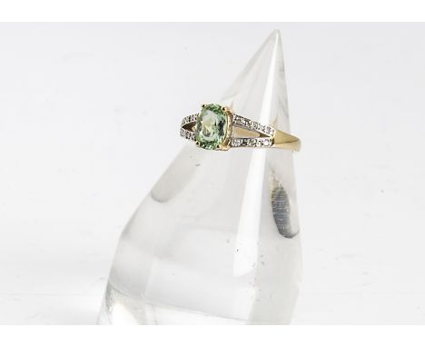 An 18ct gold peridot and diamond dress ring, the oval claw set central peridot with bifurcated diamond set shoulders all in y