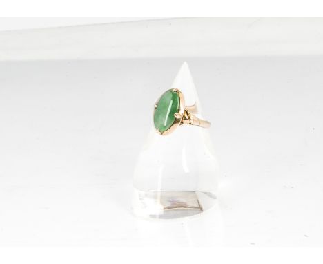 A Chinese jadeite jade and yellow metal dress ring, the oval polished jade panel in four claw setting on scroll leaf shoulder