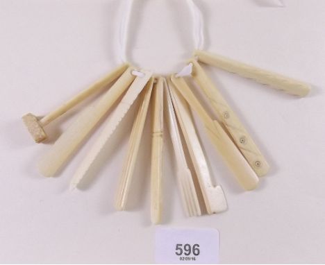 A late 19th century bunch of ivory teething tools carved as items of cutlery and tools, possibly prisoner of war work