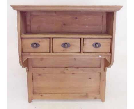 A pine wall shelf with three small drawers 