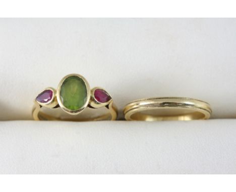 A PERIDOT AND RUBY THREE STONE RING BY THEO FENNELL the oval-shaped peridot is set with a pear-shaped ruby to each shoulder, 