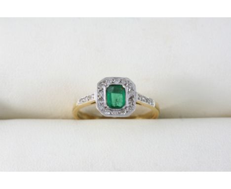 AN EMERALD AND DIAMOND CLUSTER RING the rectangular-shaped emerald is set within a surround of small diamonds, with further d