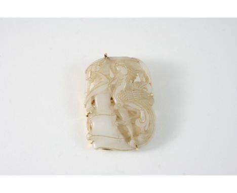 A CARVED JADE BROOCH depicting a stylised dragon on a tree trunk, 5.5 x 4cm.