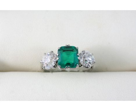 AN EMERALD AND DIAMOND THREE STONE RING set with an emerald weighing approximately 2.08 carats with a brilliant-cut diamond s