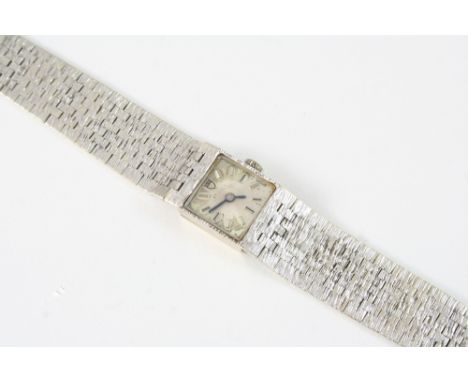 A LADY'S 9CT. WHITE GOLD WRISTWATCH  the square-shaped dial with baton numerals, on an integrated textured gold bracelet  wit