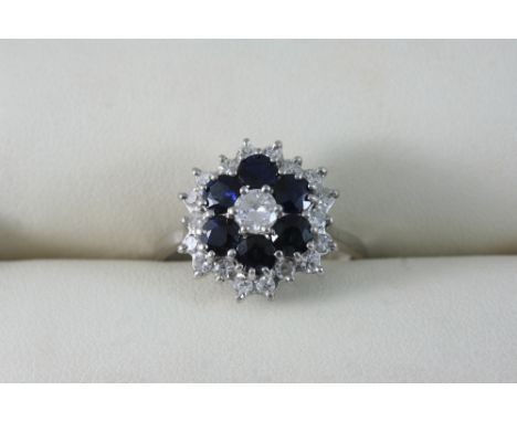 A SAPPHIRE AND DIAMOND CLUSTER RING set with circular-cut sapphires and diamonds, in 18ct. white gold. Size S.