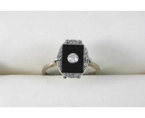 A BLACK ONYX AND DIAMOND RING the rectangular shaped black onyx panel is centred with an old brilliant-cut diamond within a s