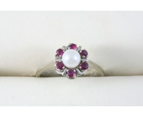 A CULTURED PEARL AND RUBY CLUSTER RING set with a cultured pearl within a surround of circular-cut rubies. Size U.