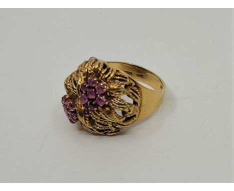 An Italian 18ct. gold and ruby ring, having pierced head fashioned twin flowers, the centres of each set cluster of seven rub