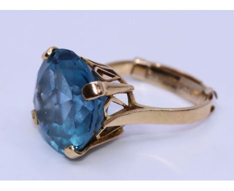 An 18ct. yellow gold blue topaz cocktail ring, four claw set round mixed cut brilliant blue topaz, gross weight 8.2g. Conditi