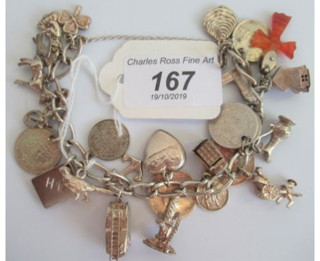 A silver charm bracelet comprising approximately 20 charms to include fire engine, water mill, telephone box and other simila