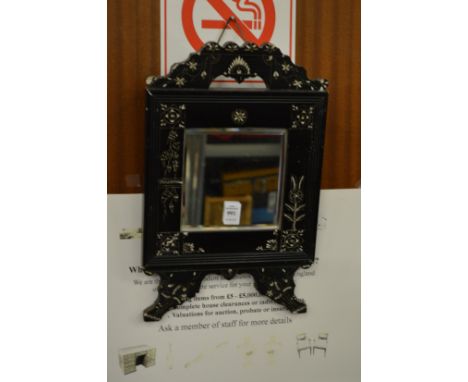 A small mirror with ebonised frame.
