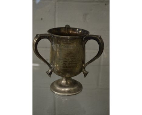 A silver three handled trophy cup.