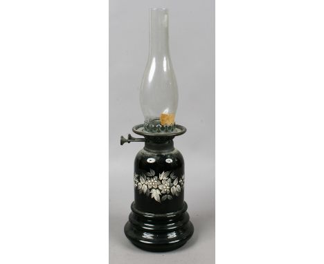 A Victorian opaque black glass oil lamp, decorated in white enamel with flowers.