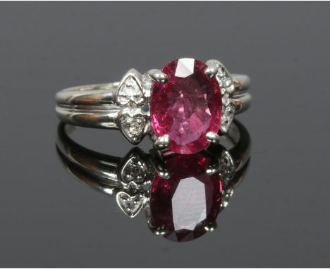 A 9ct white gold ruby ring with reeded shoulder each set with a pair of diamonds, size N.