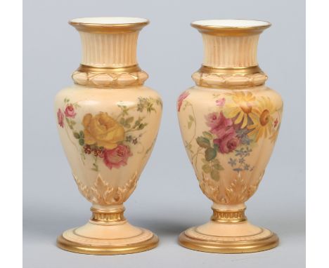A pair of Royal Worcester blush ground specimen vases, edged in gilt and painted with flowers. Printed puce marks, date codes