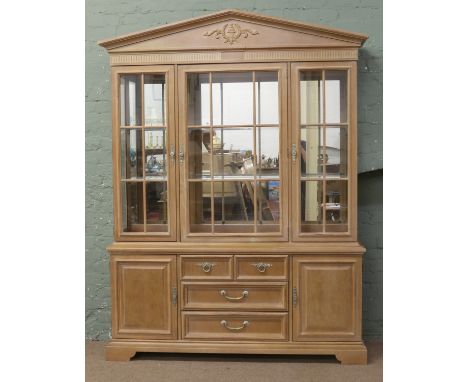 A Stanley furniture limed oak neo-classical style large display cabinet with triangular pediment and raised on bracket suppor