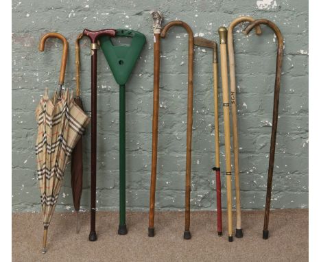 A bundle of walking sticks and umbrellas one stick with a composite topper formed as an eagle.