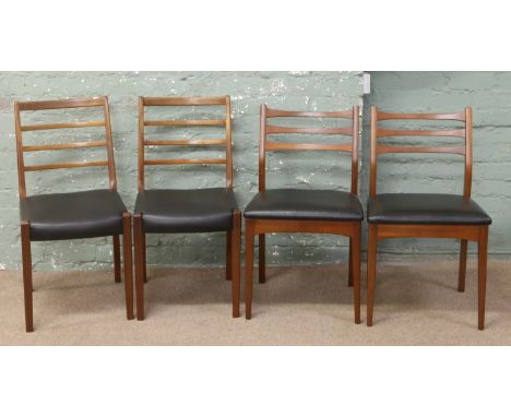 A set of four 1980s teak ladder back chairs with black leatherette seats.