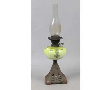 A Victorian oil lamp with opaque glass font enamelled with pendants and raised on a pierced cast iron base.