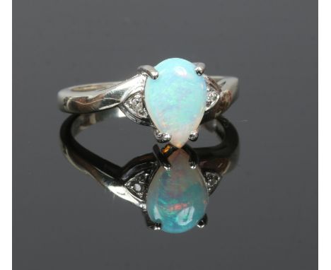 A 9ct white gold ring set with a pear cut opal flanked by diamonds, size M.