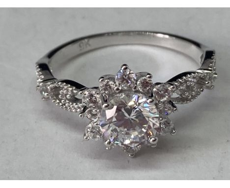 A WHITE METAL RING WITH ONE CARAT OF MOISSANITE IN A CLUSTER DESIGN AND ON THE DECORATIVE SHOULDERS SIZE Q/R 