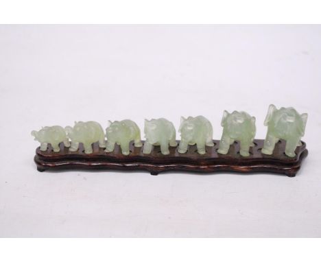 SEVEN GRADUATING JADE ELEPHANTS ON A WOODEN PLINTH (1 A/F) 