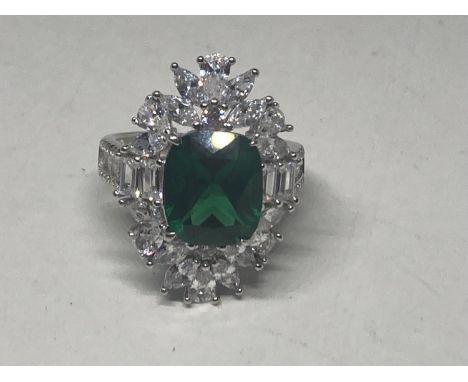 A WHITE METAL RING WITH A LARGE CENTRE LABORATORY GROWN EMERALD SURROUNDED BY CLEAR STONES SIZE S 