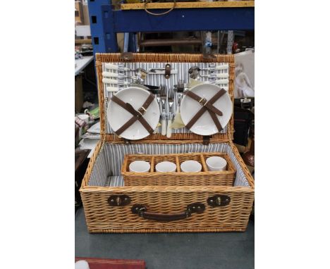 A LARGE WICKER PICNIC HAMPER CONTAINING CERAMIC CUPS AND PLATES, PLUS CUTLERY, A BOTTLE OPENER AND COTTON NAPKINS 