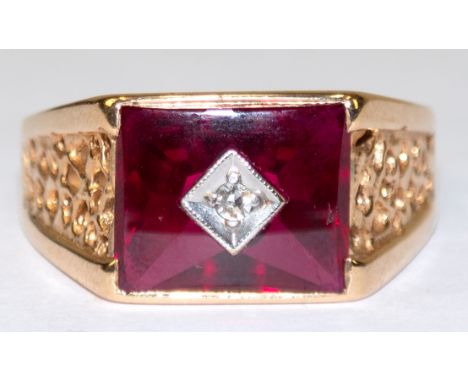 Ring, 585er GG (geprüft), rechteckiger Ringkopf besetzt mit 1 roten Schmuckstein und 1 mittigem Brillanten von ca. 0,025 ct.,