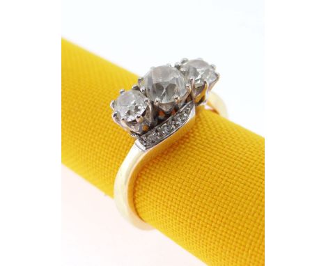 18CT GOLD THREE STONE DIAMOND RING, the three primary stones (totalling 1.0cts approximately) on a twist shank with diamond c