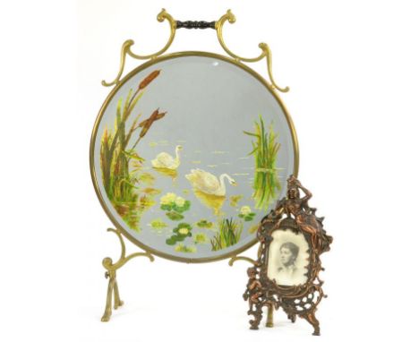 A VICTORIAN CIRCULAR GLASS AND MIRROR INSET FIRESCREEN, PAINTED WITH SWANS, 71CM H AND AN ORNATE CAST IRON FIGURAL PHOTOGRAPH