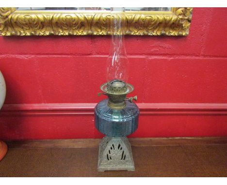 An oil lamp on cast floral design base with blue glass reservoir with chimney