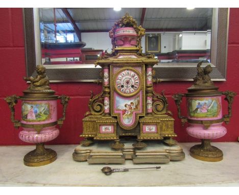 An early 20th Century French hand painted ceramic and ormolu clock garniture comprising mantel clock and pair of lidded urns 
