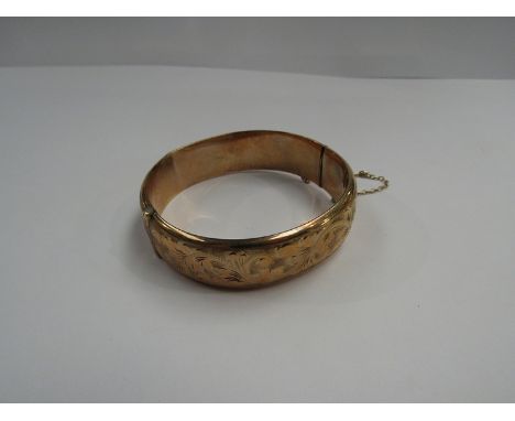 A 9ct gold stiff-hinge bangle with scrolled foliate engraved design, 18.9g