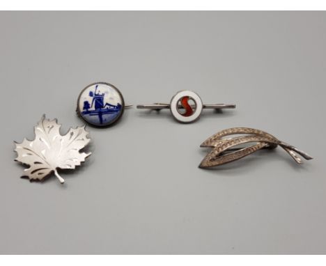 Silver brooches to include one with delft plaque, enamel and maple leaf