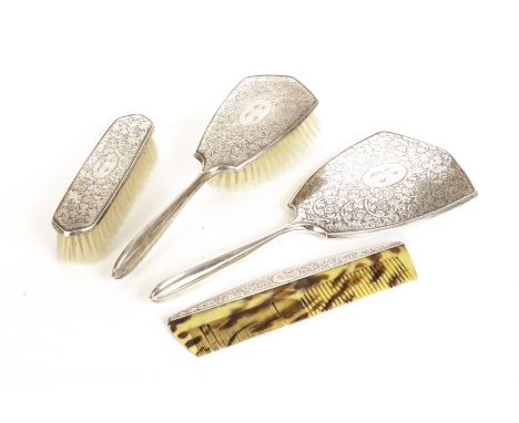 A silver dressing table set, comprising brush, mirror, clothes brush, and comb, all with chased arabesque decoration and mono