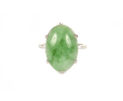 A Chinese hardstone dress ring, the large polished oval possibly jade green stone in white metal ring mount