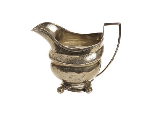 A Georgian period silver milk jug, helmet shaped having engraved designs, on four ball supports, bearing Newcastle hallmarks 