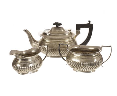 A George V silver three piece tea set by W.H.H, the squat form teapot, milk jug and sugar basin with gadrooned lowers, the te