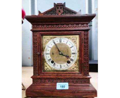 An oak mantel clock with carved decoration and architectural pediment (no finials) having square brass dial and Westminster c